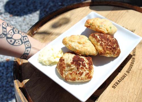 A plate of freshly baked scones with a dollop of butter, resting on a wooden surface with a tattooed arm in the background.