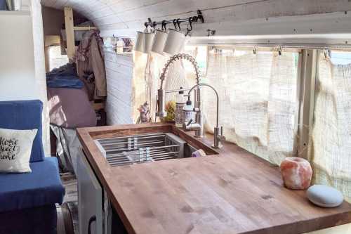 Cozy interior of a tiny home on wheels, featuring a wooden kitchen counter, sink, and soft natural lighting.