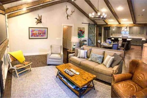 Cozy living room with a sofa, armchair, coffee table, and rustic decor, featuring wooden beams and a warm atmosphere.