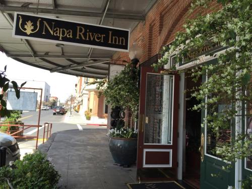 Entrance of Napa River Inn with a sign and greenery, showcasing a welcoming atmosphere.