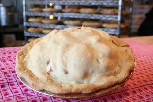A freshly baked pie with a golden, domed crust, sitting on a pink patterned tablecloth.