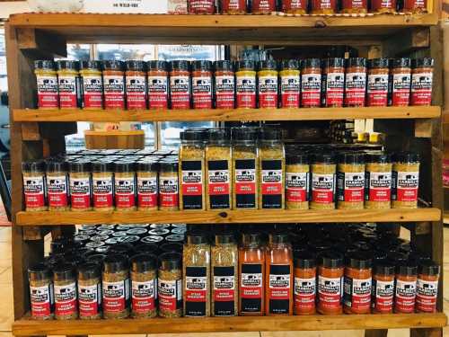 A wooden shelf displaying various spice jars with colorful labels in a store.