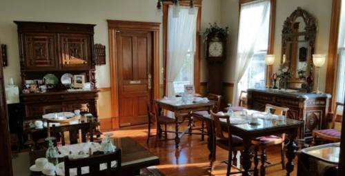 A cozy dining room with wooden furniture, elegant decor, and large windows letting in natural light.