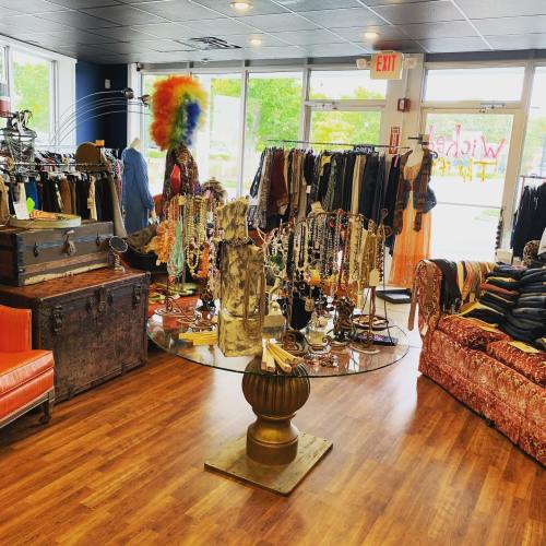 A vibrant boutique interior featuring colorful clothing, jewelry displays, and a cozy seating area.