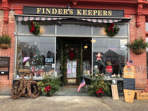 A charming storefront with holiday decorations, featuring a sign that says "Finders Keepers" and an open sign.