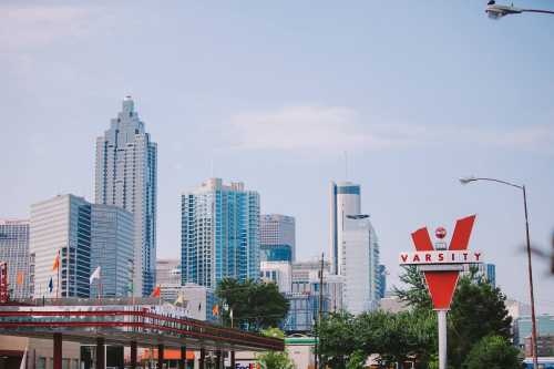 A city skyline featuring modern skyscrapers, with a prominent vintage Varsity sign in the foreground.