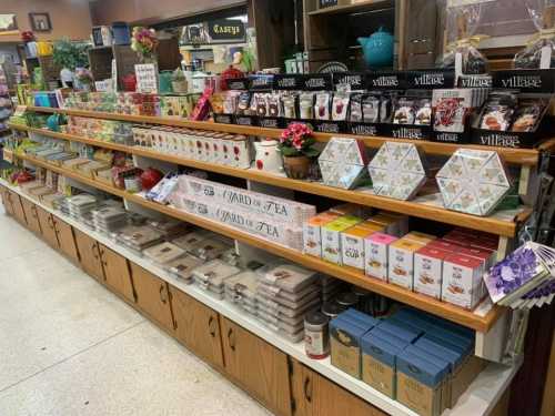 A display of various tea products and gifts on wooden shelves in a store, featuring colorful packaging and decorative items.