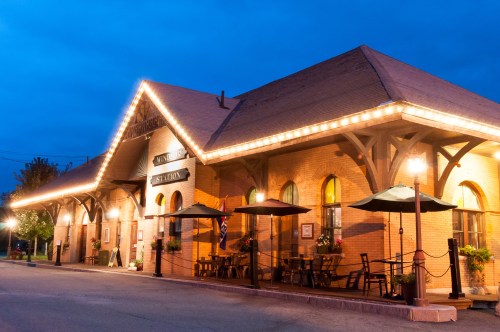 Historic train station illuminated at night, featuring outdoor seating and decorative lights.