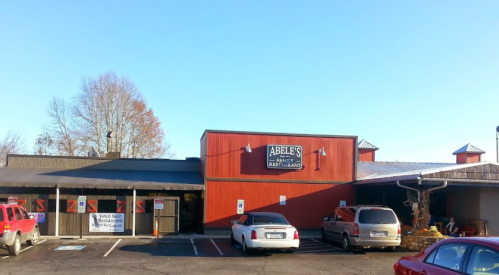 Exterior of Abeles Family Restaurant, featuring a red building with a sign, parked cars, and clear blue sky.