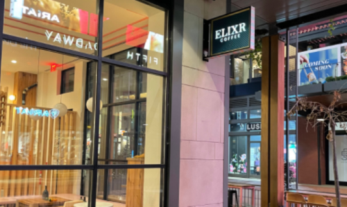 Exterior view of Elixir Coffee shop with large windows and a modern design, located on a busy street.