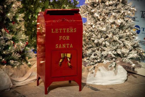 A red mailbox labeled "Letters for Santa" surrounded by snowy Christmas trees.
