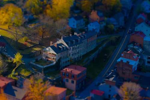 Aerial view of a quaint neighborhood with colorful autumn trees and a historic building surrounded by houses.