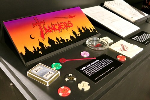 Display featuring "Tangers" game items, including chips, a bowl, and a sign, set against a colorful skyline backdrop.