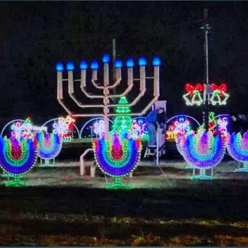 Colorful holiday lights display featuring a menorah and festive decorations in a nighttime setting.
