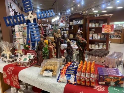 A festive display featuring a blue windmill, holiday treats, and decorative figurines in a cozy shop setting.
