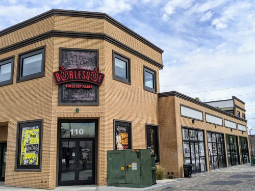 Exterior of the Burlesque Hall of Fame building, featuring a brick facade and large windows with colorful signage.