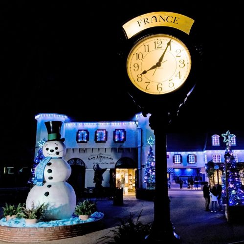 A clock showing the time near a snowman and festive decorations in a nighttime scene labeled "France."