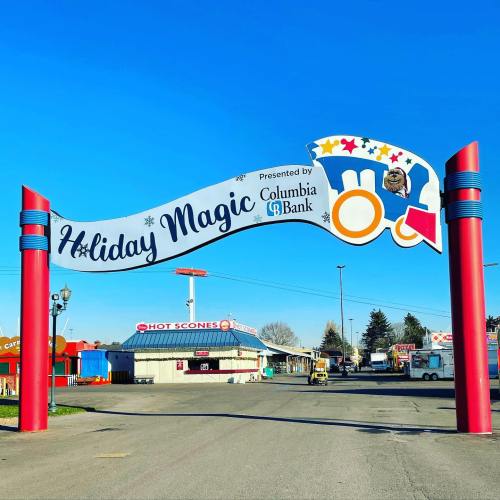 A colorful archway reading "Holiday Magic" with festive decorations, leading to a fairground area.