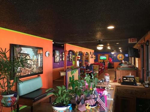 Colorful restaurant interior with vibrant orange and purple walls, plants, and patrons enjoying their meals.