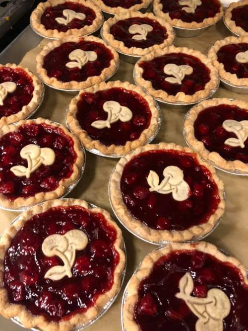 A collection of cherry pies with decorative crusts, arranged neatly on a table.