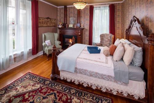 Cozy bedroom featuring a wooden bed, armchair, fireplace, and patterned wallpaper, with soft lighting and a warm atmosphere.