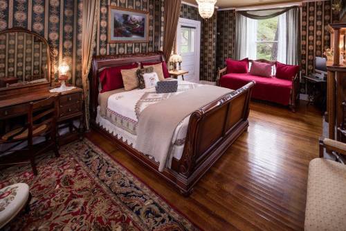 Cozy bedroom featuring a wooden bed, vintage decor, a red sofa, and a patterned rug, with natural light from a window.