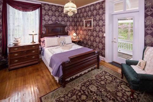 Cozy bedroom with vintage decor, featuring a wooden bed, dresser, and a green armchair against patterned wallpaper.