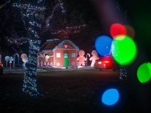 A festive scene featuring a gingerbread house and inflatable gingerbread figures, surrounded by colorful holiday lights.
