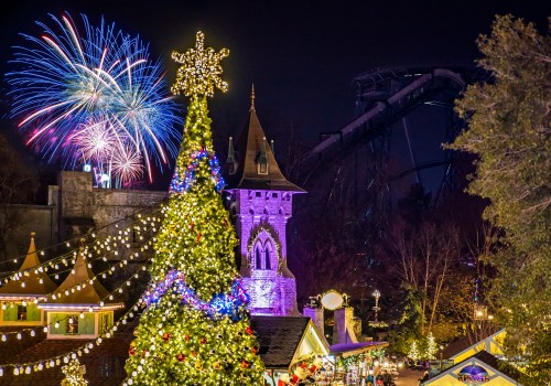 A festive scene with a decorated Christmas tree, colorful fireworks, and a theme park ride in the background at night.