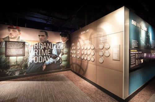 Exhibit on organized crime, featuring images of individuals and informational panels on global law and crime today.