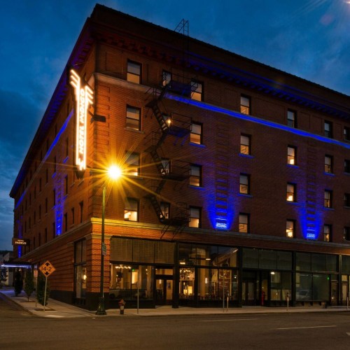 A historic brick building illuminated at night, featuring blue lights and a corner entrance.