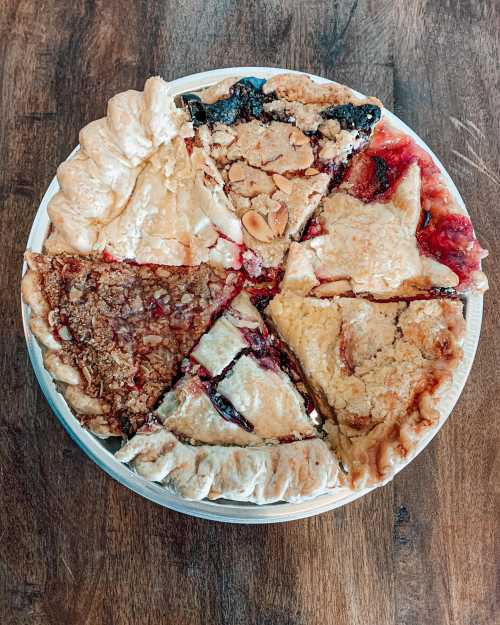 A round pie with eight slices, each featuring different fillings and crust styles, on a wooden surface.