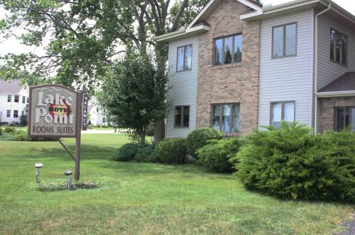 Sign for Lake Point Rooms & Suites in front of a two-story brick building, surrounded by green grass and trees.