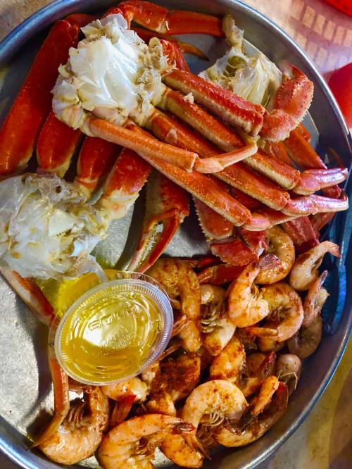 A platter of seafood featuring crab legs, shrimp, and a side of dipping sauce.