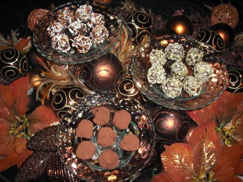 Three glass bowls filled with chocolate truffles and coconut treats, surrounded by decorative autumn leaves and ornaments.