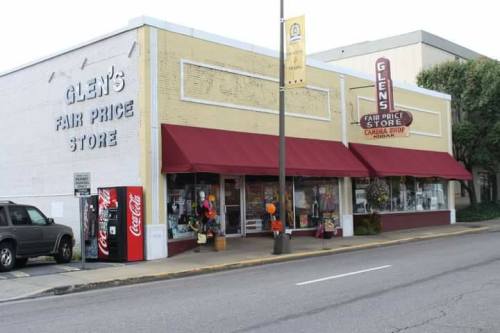 Exterior of Glen's Fair Price Store, featuring a yellow building, maroon awnings, and a Coca-Cola vending machine outside.