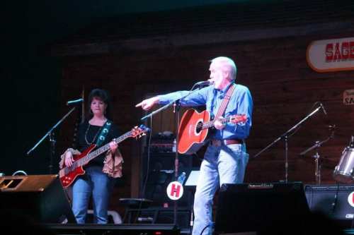 A musician performs on stage with a guitar, while a bassist stands nearby, both engaged in a lively performance.