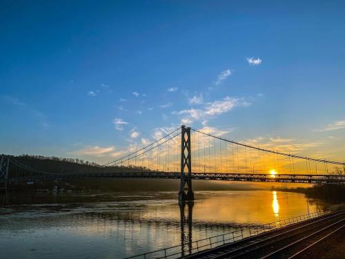 A sunset over a river, with a bridge silhouetted against a colorful sky and calm water reflecting the light.