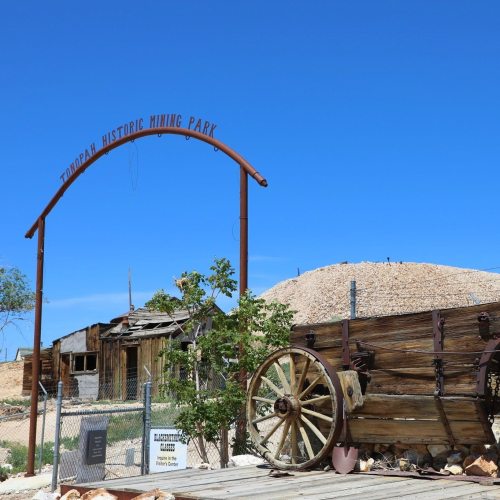 Entrance to Tonopah Historic Mining Park, featuring a wooden cart and a clear blue sky in the background.