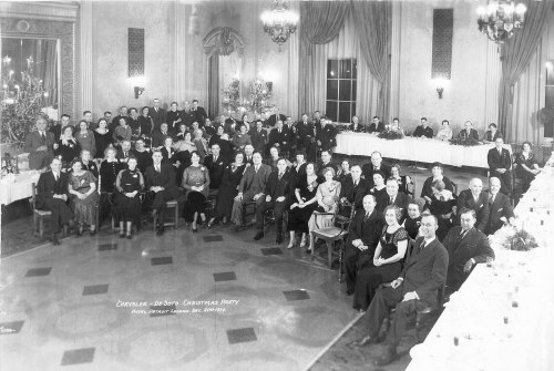 Black and white photo of a large group at a formal Christmas party, seated in a decorated banquet hall.
