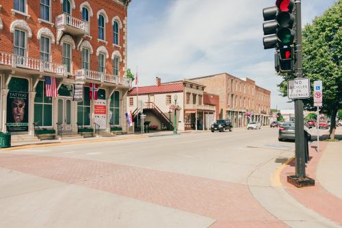 A quiet street scene featuring brick buildings, traffic lights, and flags in a small town.