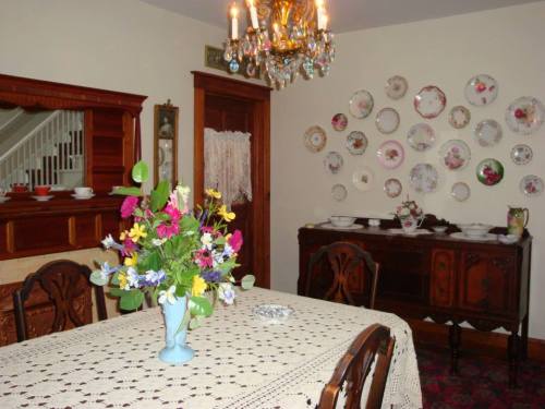 A cozy dining room featuring a floral centerpiece, vintage plates on the wall, and elegant furniture.