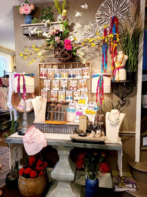 A vibrant display of jewelry and accessories, adorned with flowers and colorful ribbons, set against a rustic backdrop.