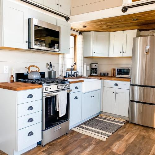 A modern kitchen with light blue cabinets, stainless steel appliances, and wooden accents, featuring a cozy rug.