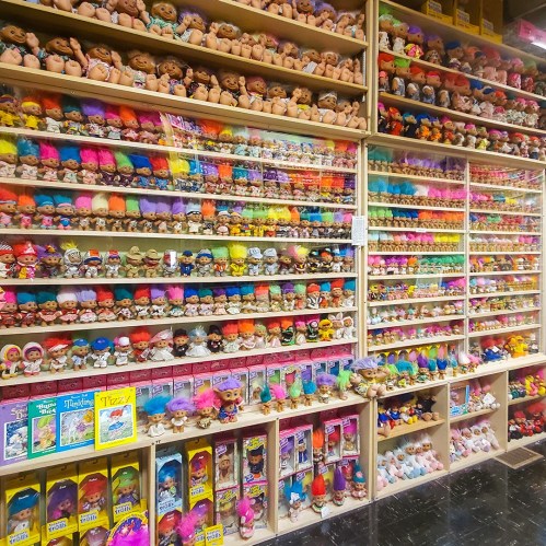 A colorful display of various troll dolls and collectibles arranged on shelves in a store.