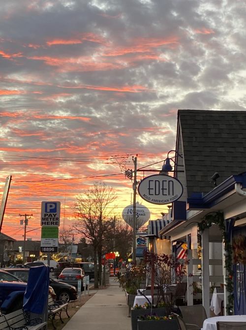 A street view at sunset featuring a restaurant named "Eden" and colorful clouds in the sky.