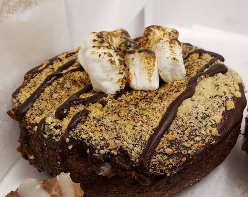A chocolate dessert topped with toasted marshmallows and graham cracker crumbs, drizzled with chocolate sauce.