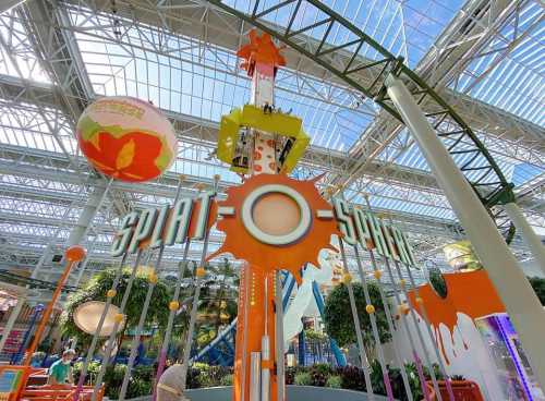 Colorful amusement ride titled "Splat-O-Splat" in a bright indoor space with a glass ceiling.