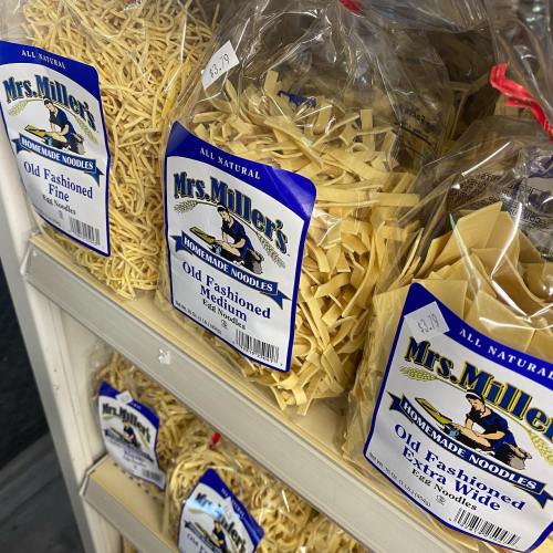 A shelf displaying bags of Mrs. Miller's homemade noodles in various shapes and sizes, labeled with prices.