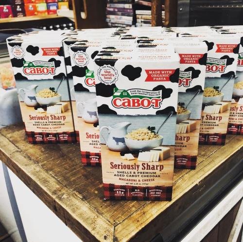 A display of Cabot Seriously Sharp macaroni and cheese boxes on a wooden table.
